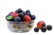 Plums and prunes in a vase for fruit on a white background.