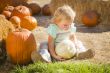 Adorable Baby Girl Holding a Pumpkin at the Pumpkin Patch