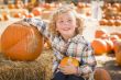 Little Boy Sitting and Holding His Pumpkin at Pumpkin Patch