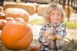 Little Boy Sitting and Holding His Pumpkin at Pumpkin Patch