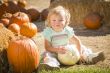 Adorable Baby Girl Holding a Pumpkin at the Pumpkin Patch