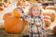 Little Boy Sitting and Holding His Pumpkin at Pumpkin Patch