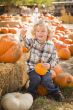 Little Boy Sitting and Holding His Pumpkin at Pumpkin Patch