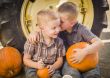 Two Boys Sitting Against Tractor Tire Holding Pumpkins Whisperin
