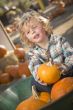 Little Boy Sitting and Holding His Pumpkin at Pumpkin Patch
