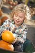 Little Boy Sitting and Holding His Pumpkin at Pumpkin Patch
