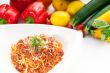 spaghetti with bolognese sauce and fresh vegetables on backgroun