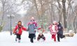 Group of children and mother playing on snow in winter time