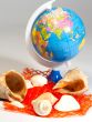 Seashells and small globe on a book with a geographical map.