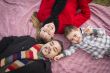 Family in Winter Clothing Laying on Their Backs in Park