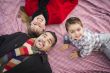 Family in Winter Clothing Laying on Their Backs in Park