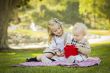 Little Girl Gives Her Baby Brother A Gift at Park