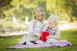 Little Girl Gives Her Baby Brother A Gift at Park