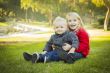 Little Girl with Baby Brother Wearing Coats at the Park