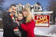 Family in Front of Sold Real Estate Sign and House