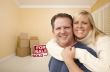 Couple in New House with Boxes and Sold Sale Sign