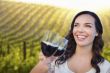 Young Woman Enjoying Glass of Wine in Vineyard With Friends