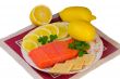 Salmon fillet and lemons on a platter on a white background.
