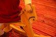 A small girl is riding wooden horse-rocking chair.