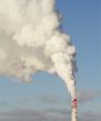 Smokestacks with white steam in the blue sky.