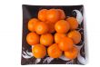 Large ripe tangerines in a glass dish on a white background.