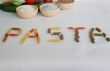 Word PASTA with vegetables and cereals in the background