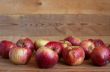Red apples lie on a wooden surface