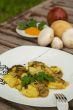 Baked potatoes with mushrooms and parsley on the white plate.