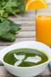 Spinach cream soup in the white  plate and a glass of fresh oran