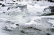 Ice covers rocks in a slow motion river in the winter 