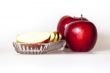 Two ripe red apples and segments of apple on a plate