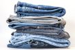 Pile of jeans of various colors on a counter in shop