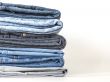 Pile of jeans of various colors on a counter in shop