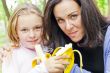 Mother and daughter eating banana