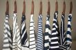 A row of navy striped tops for women on wooden hangers in a clos